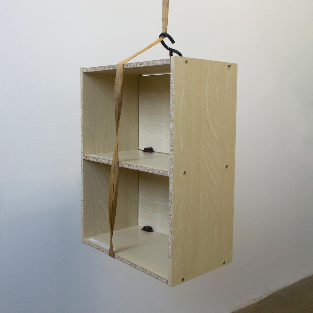 a full view of the back of the empty, unfinished cabinet, hanging mid air from the moving cable